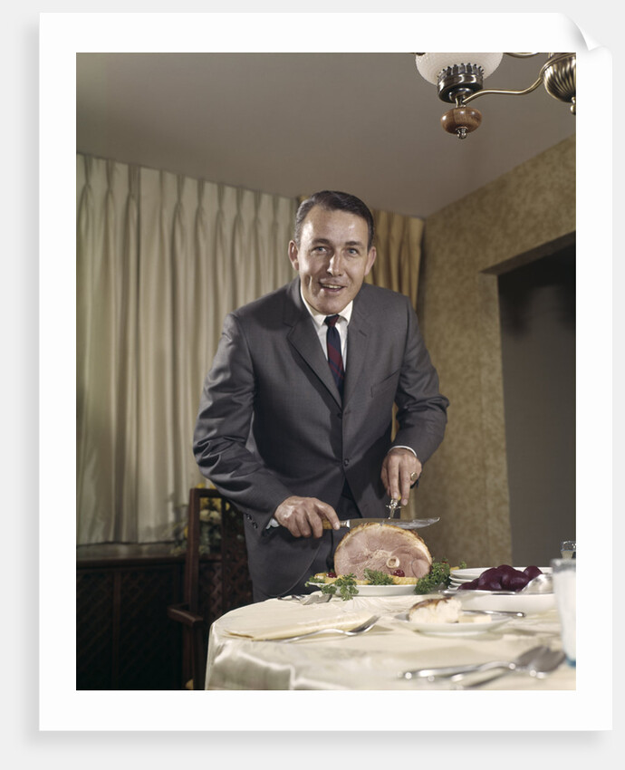 1960s man carving ham dinner looking at camera by Anonymous