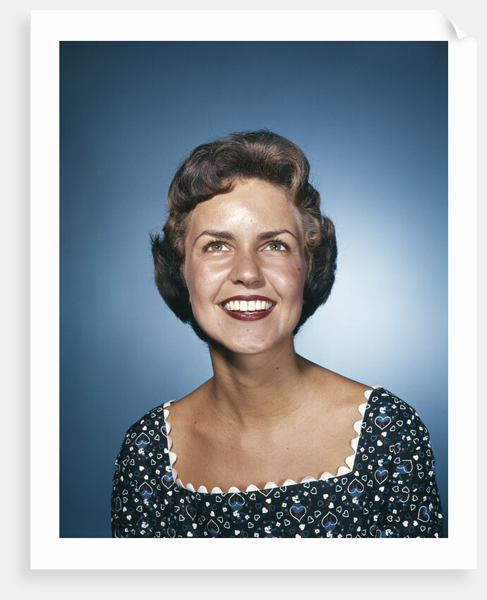 1960s smiling brunette woman in print dress looking up by Anonymous