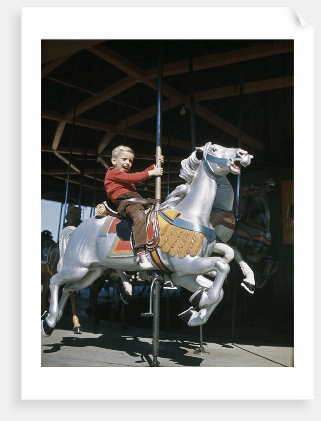 1950s excited boy riding carved wooden carousel merry-go-round horse by Anonymous
