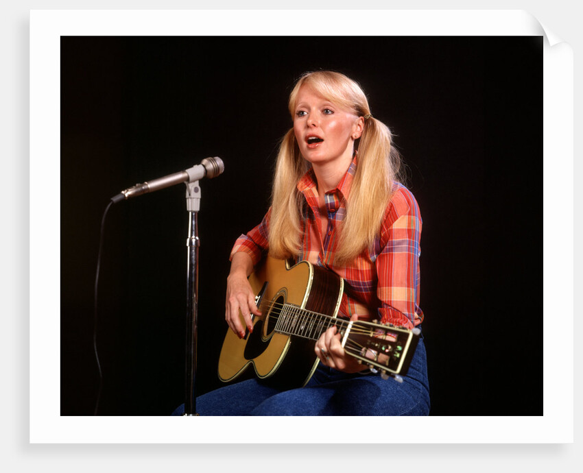 1970s blond young woman ponytails plaid shirt jeans play guitar singing microphone folk singer singers by Anonymous