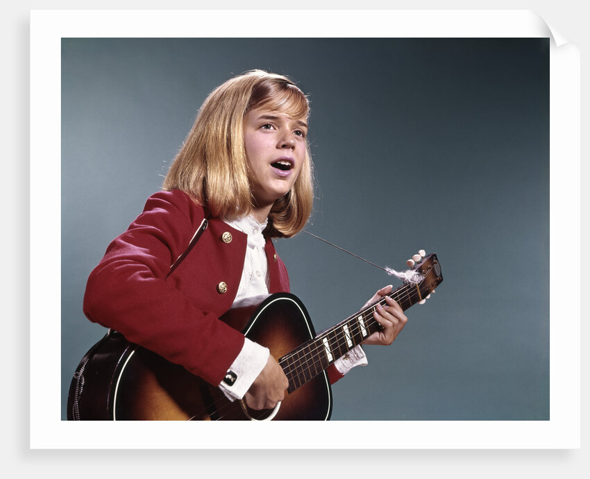 1960s blond teenaged girl singing and playing acoustic guitar by Anonymous
