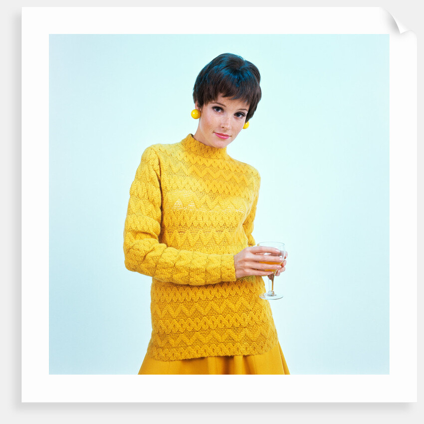 1960s brunette woman short pixie hair style yellow knit sweater earrings holding wine glass by Anonymous
