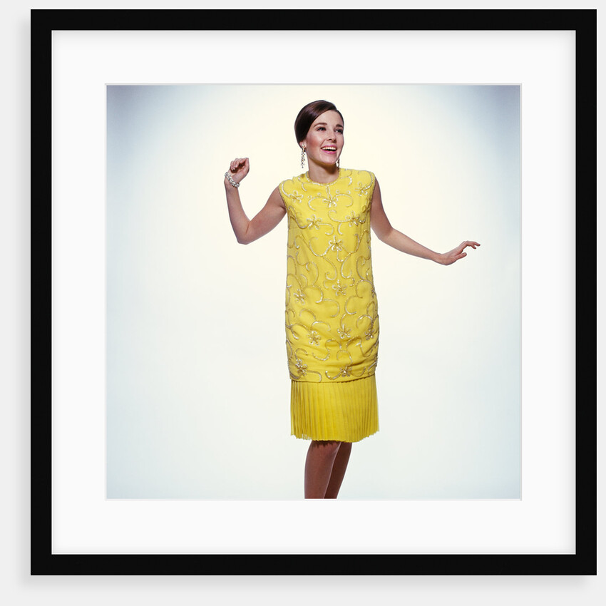 1960s smiling brunette woman modeling yellow sequined cocktail dress clothes by Anonymous