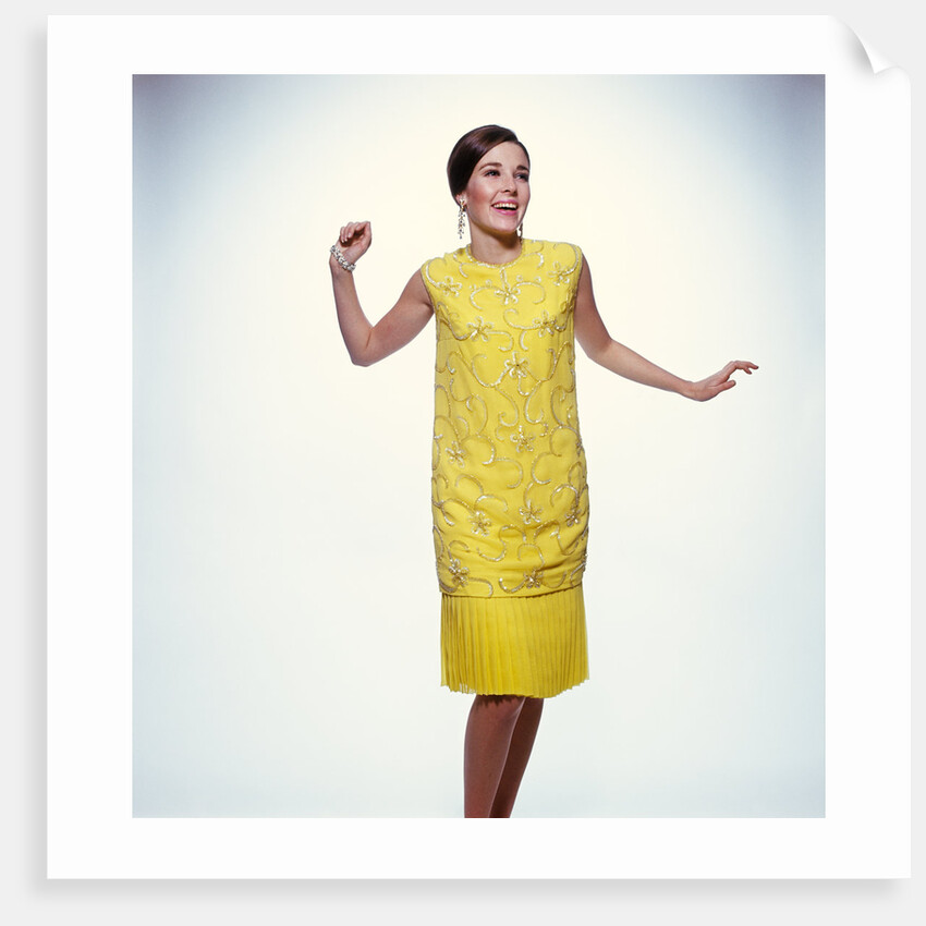 1960s smiling brunette woman modeling yellow sequined cocktail dress clothes by Anonymous