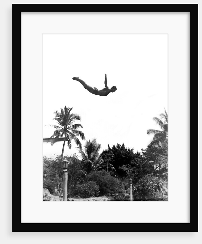 1940s man poised midair arms out jumping from diving board into pool by Anonymous
