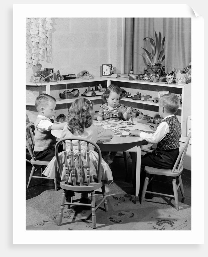 1950s 4 pre-school age children seated at small round table putting together jigsaw puzzle by Anonymous