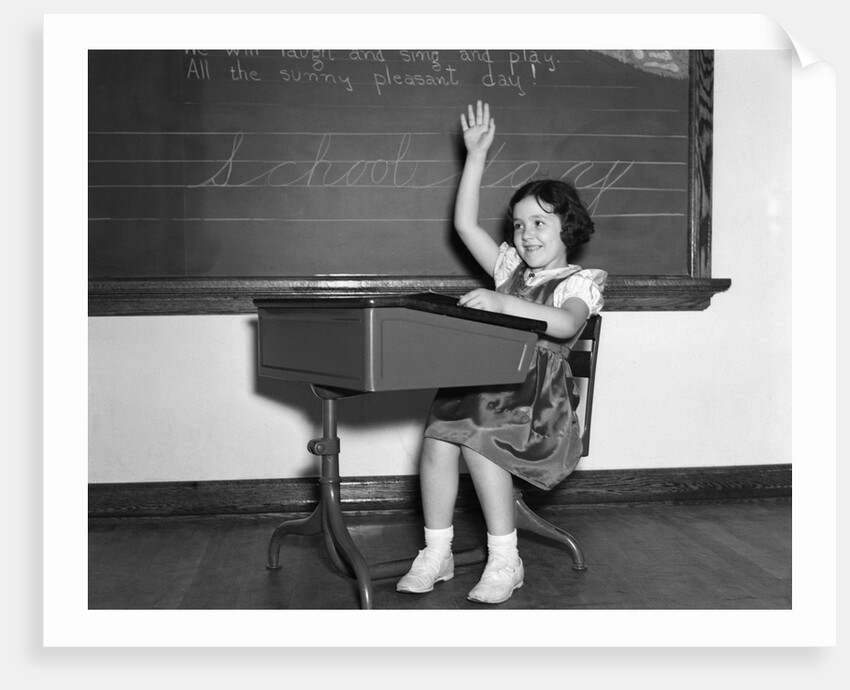 1930s 1940s smiling girl sitting at desk raising her hand by Anonymous