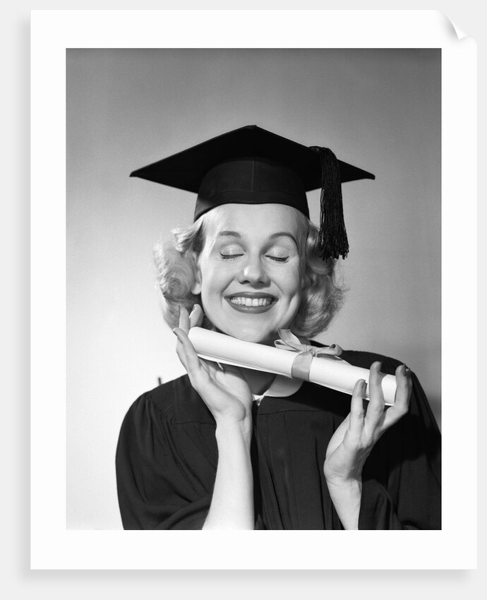 1950s smiling woman teenage girl eyes closed holding diploma graduate wearing cap gown by Anonymous