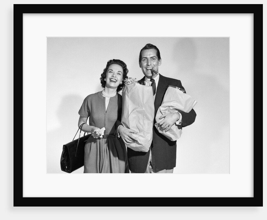 1950s couple smiling woman man carrying grocery bags smoking cigar looking at camera by Anonymous