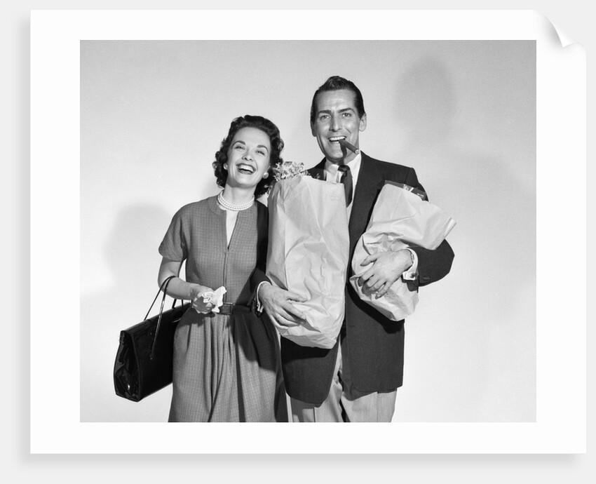 1950s couple smiling woman man carrying grocery bags smoking cigar looking at camera by Anonymous