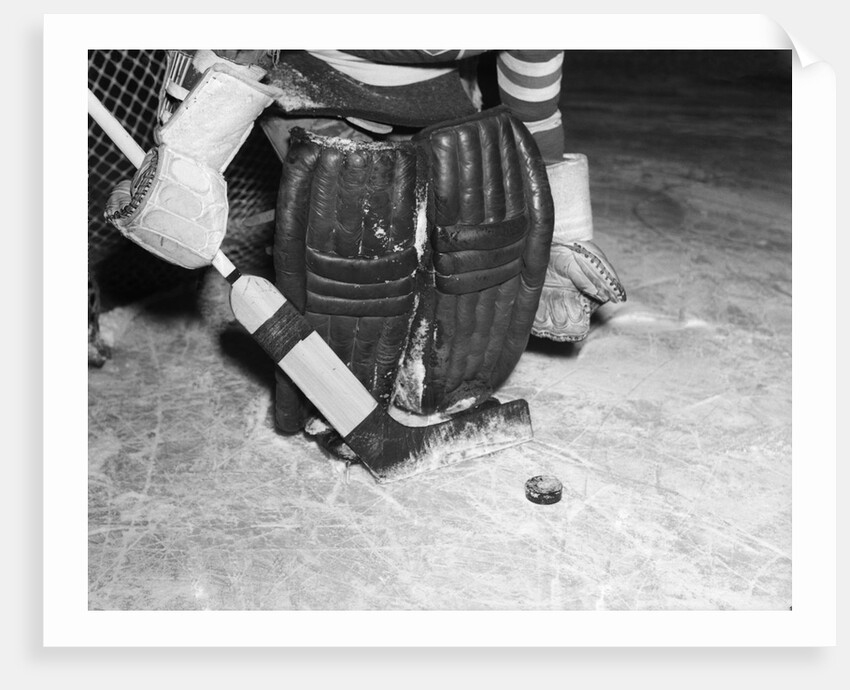 1940s 1950s close-up of padded goalie shown waist-down holding stick with puck in front of him by Anonymous