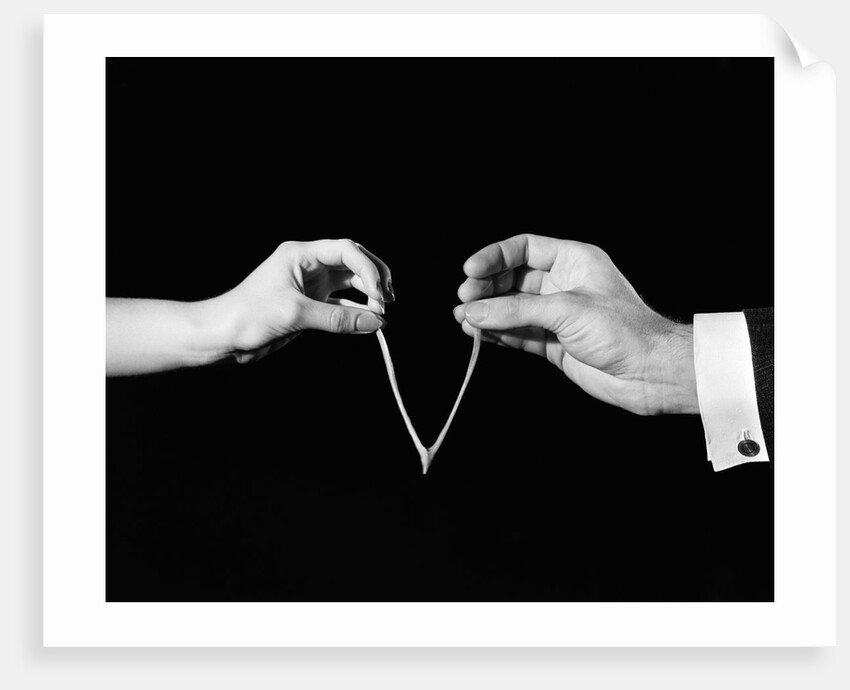 1940s man's & woman's hands pulling on either side of wishbone by Anonymous