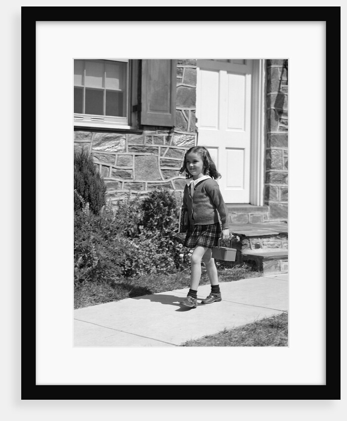 1940s little girl walking to school outside of home doorway carrying lunch box by Anonymous