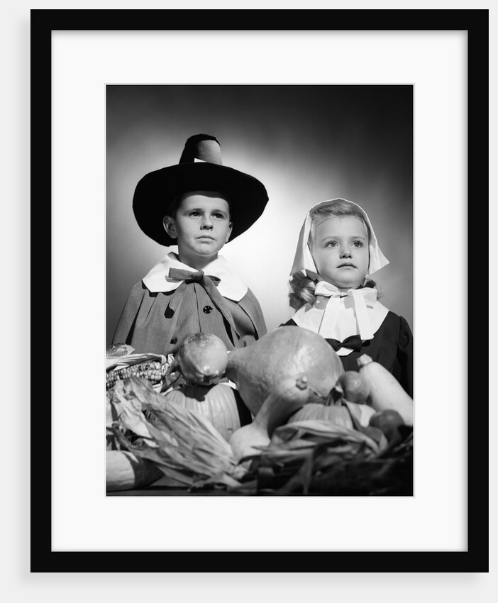 1950s boy & girl in pilgrim costumes with harvest arrangement on table by Anonymous