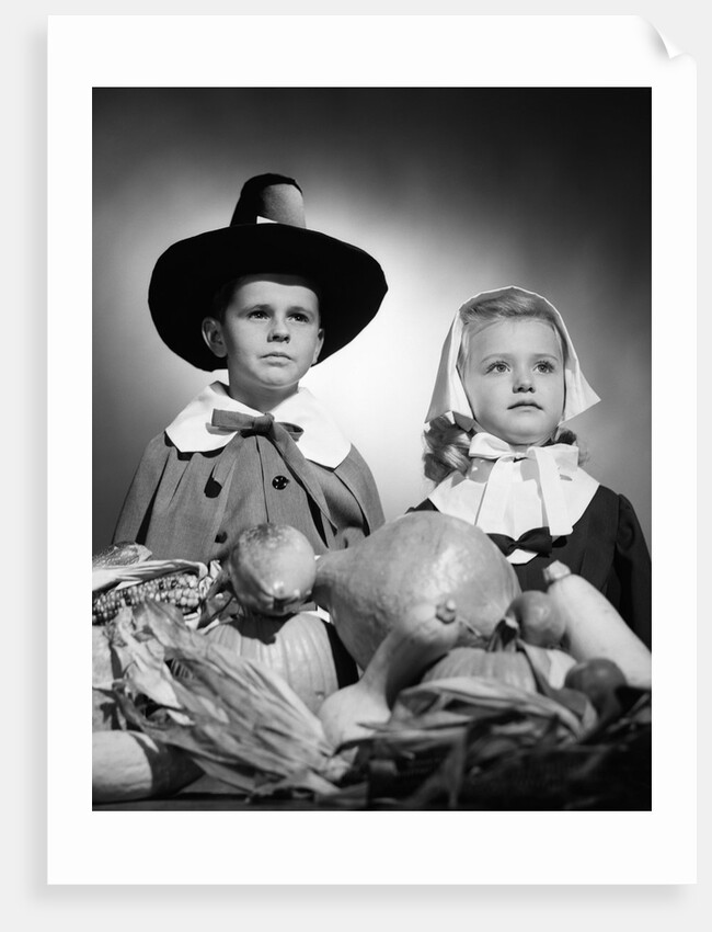 1950s boy & girl in pilgrim costumes with harvest arrangement on table by Anonymous
