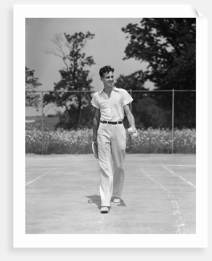 1930s man walking across tennis court holding tennis racket & balls by Anonymous