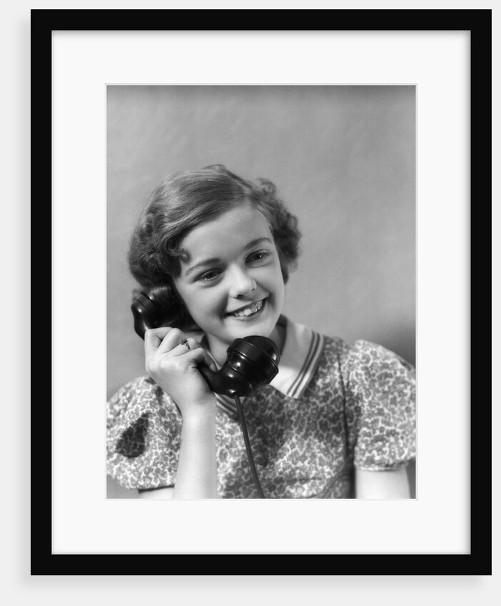 1930s teen girl smiling brunette print dress talking on telephone by Anonymous