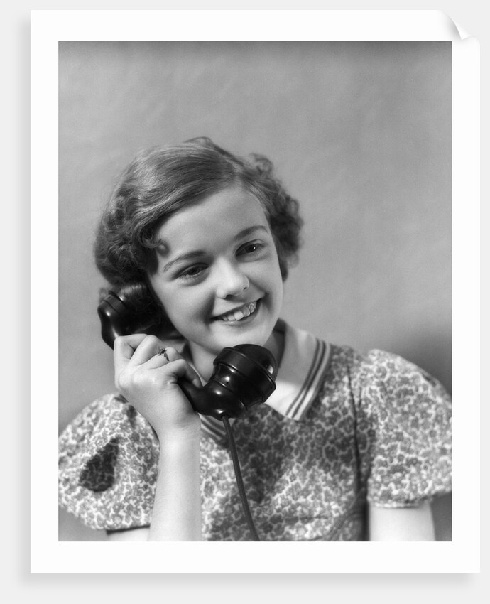 1930s teen girl smiling brunette print dress talking on telephone by Anonymous