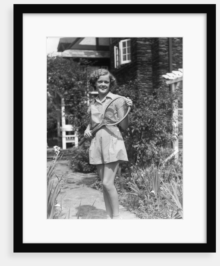 1930s teen girl brunette on sidewalk of house holding tennis racket wearing shorts by Anonymous