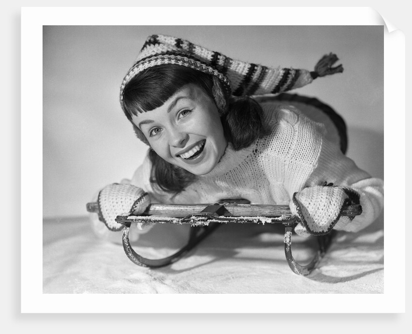 1950s smiling young teenage woman posing on sled in winter wool knit clothes looking at camera by Anonymous
