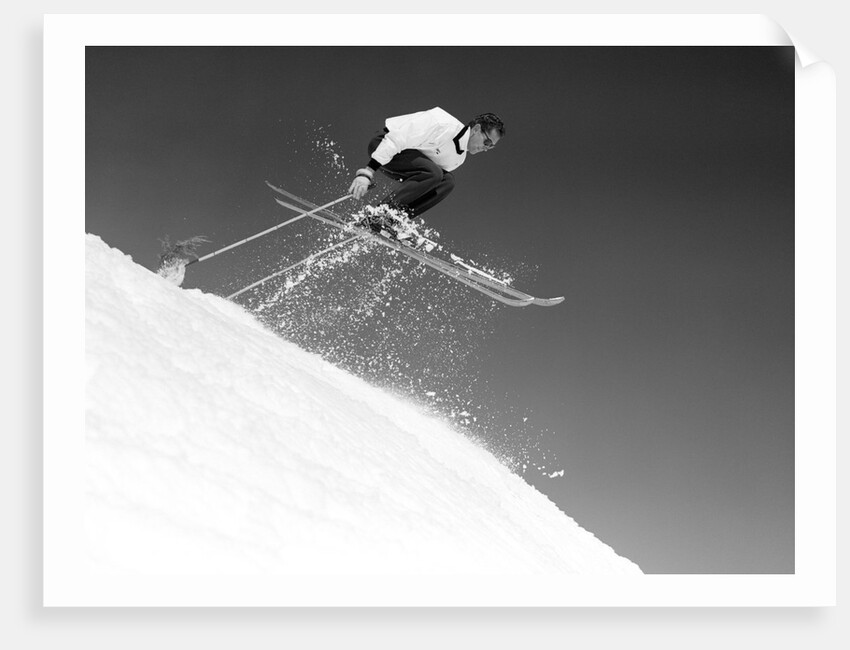 1950s man skier skiing down slope jumping into air by Anonymous