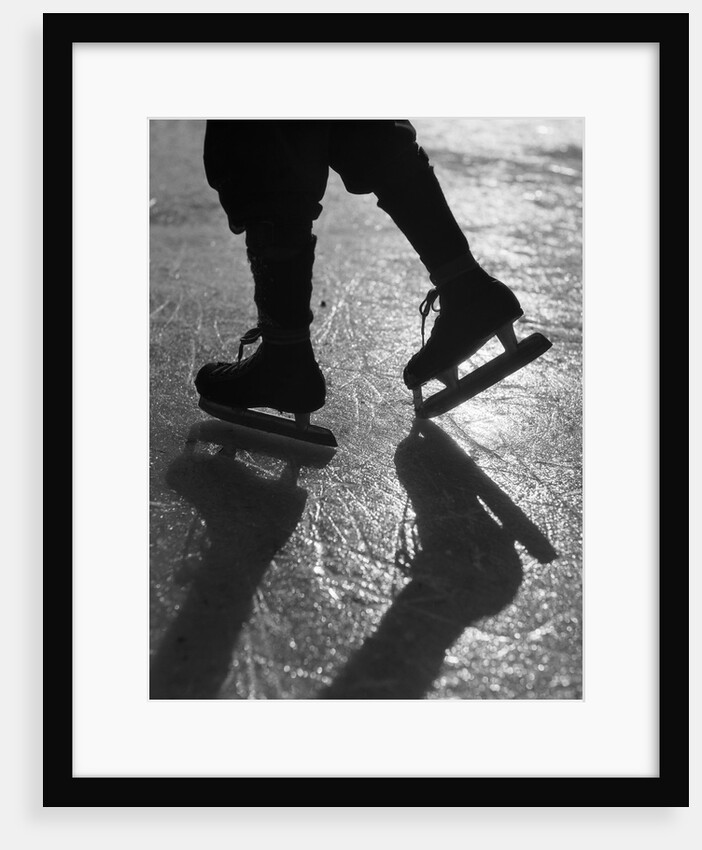 1930s silhouette figure shown from knees down wearing ice skates skating in ice sun glare by Anonymous