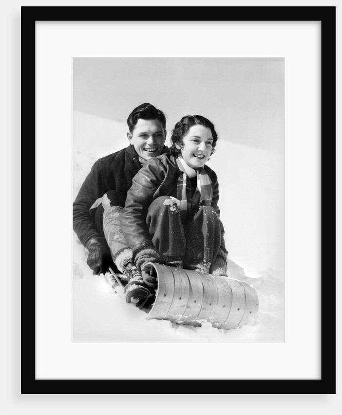 1920s 1930s smiling couple man and woman on toboggan in winter by Anonymous