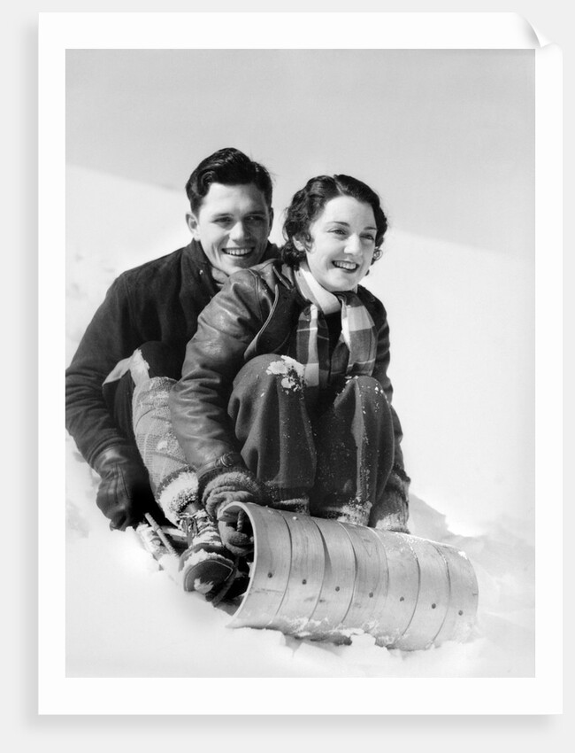 1920s 1930s smiling couple man and woman on toboggan in winter by Anonymous