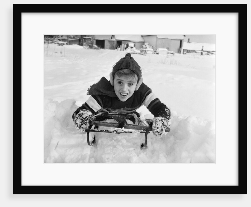 1950s boy on sled in snow looking at camera by Anonymous