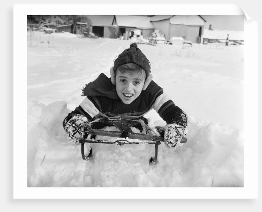 1950s boy on sled in snow looking at camera by Anonymous