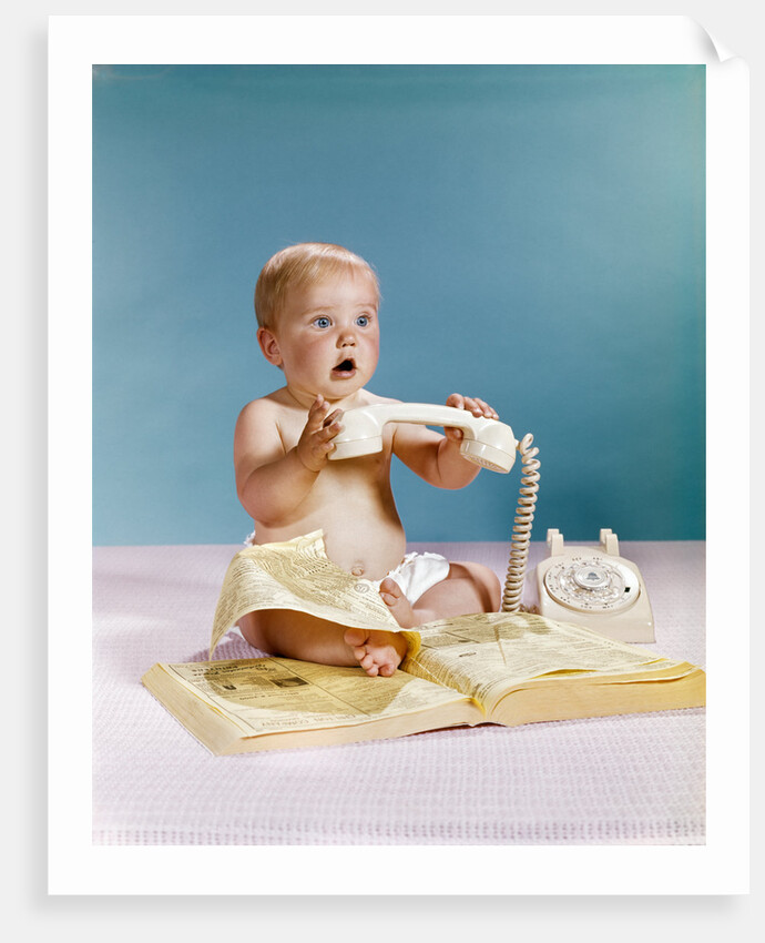 1960s baby surprised facial expression holding telephone hand set over yellow pages phone book directory by Anonymous