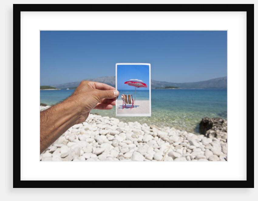 Hand holding photograph depicting deck chair and sunshade, Lumbarda, Korcula island, Croatia by Anonymous