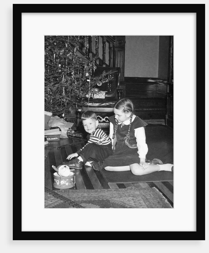 Brother and sister in front of the Christmas tree, ca. 1950 by Anonymous