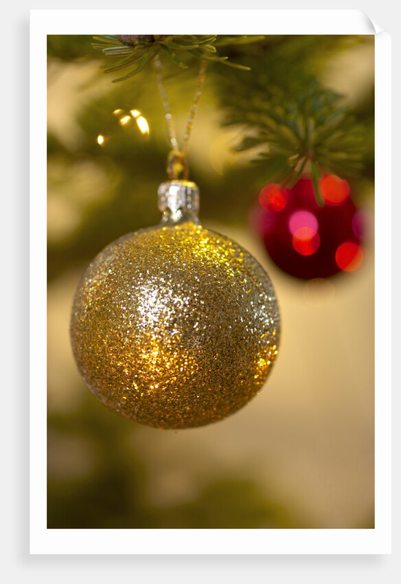 Close-up of a golden hanging Christmas bauble on blurred tree by Anonymous