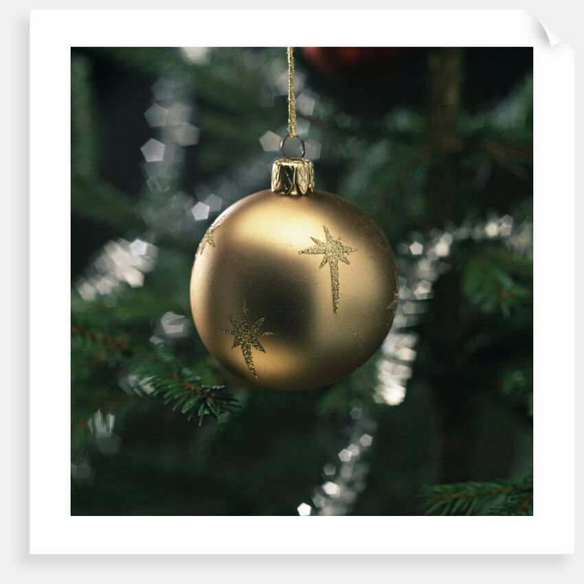Close-up of a golden hanging Christmas bauble on blurred tree by Anonymous