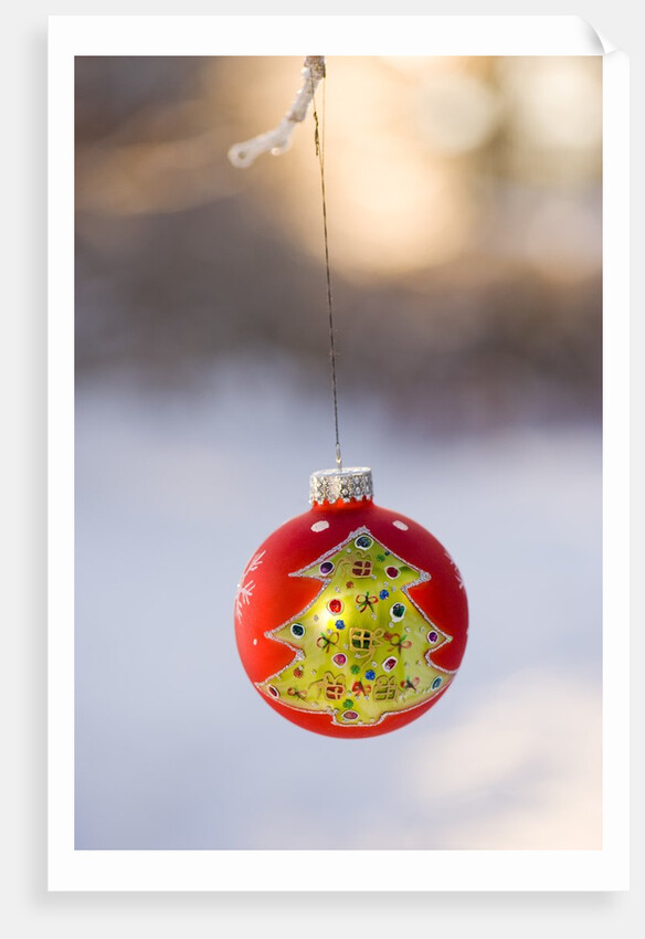 Close-up of golden Christmas tree on red bauble against blurred background by Anonymous
