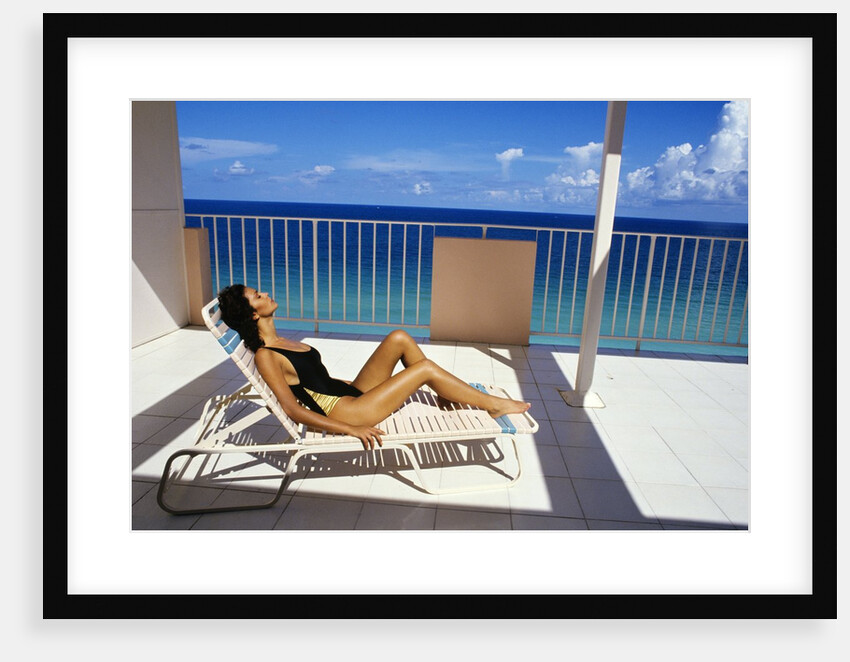 1990s Woman Wearing Black And Gold Bathing Suit Sunbathing On Patio In Deck Chair by Anonymous