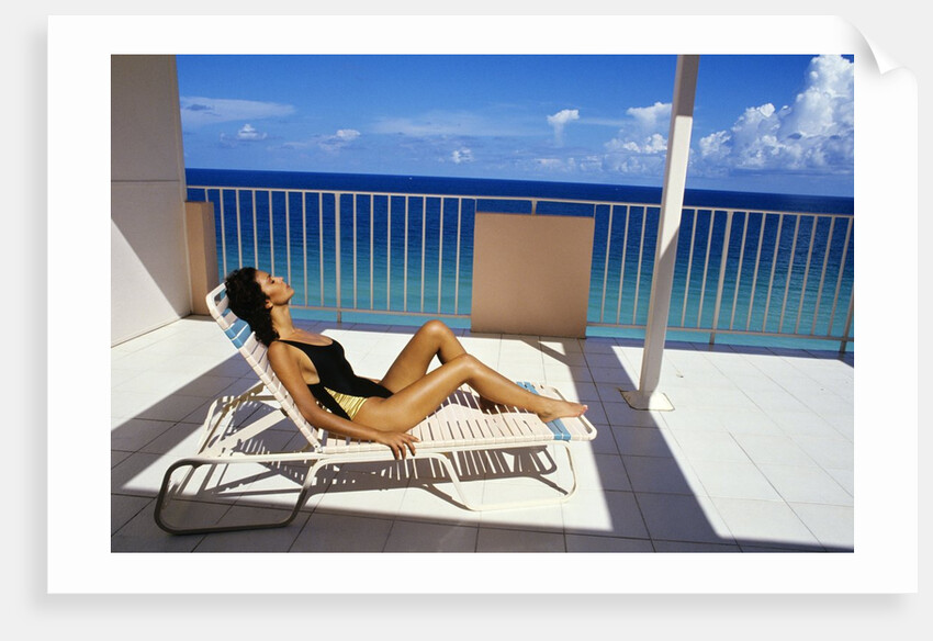 1990s Woman Wearing Black And Gold Bathing Suit Sunbathing On Patio In Deck Chair by Anonymous