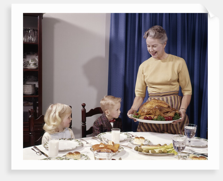 1960s Grandmother Presenting Roasted Turkey To Children At Dining Room Table by Anonymous