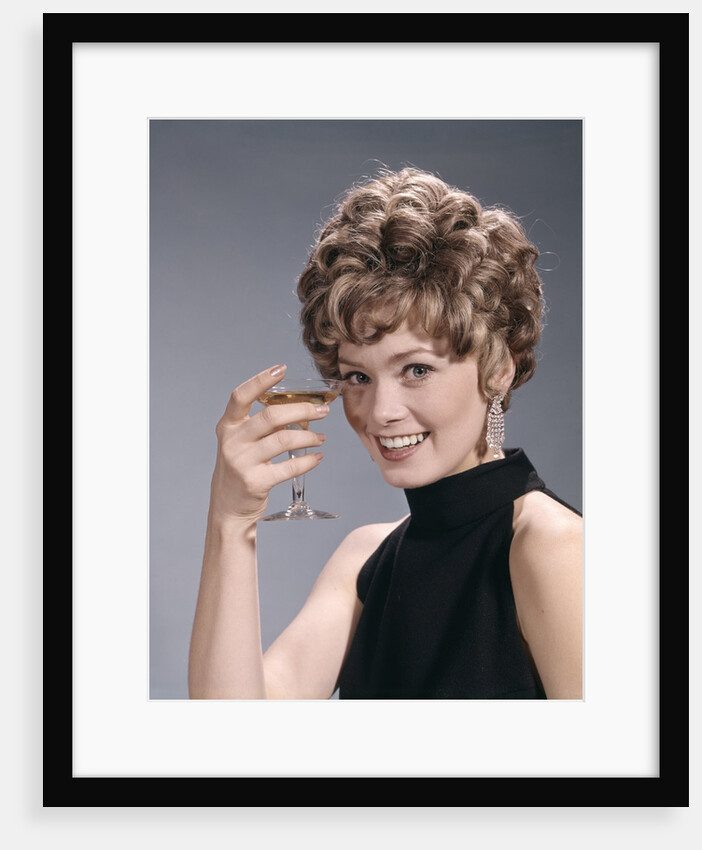 1960s Portrait Glamourous Woman In Black Dress Earrings Holding A Cocktail Looking At Camera by Anonymous
