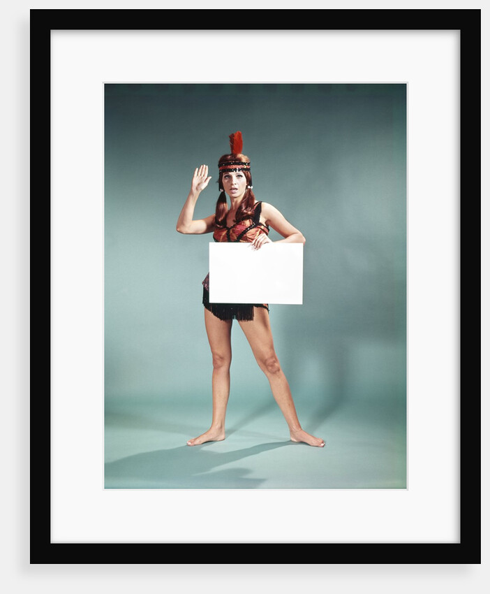 1960s 1970s Character Woman Wearing Native American Feather Headdress Making How Gesture Holding Blank Sign Looking At Camera by Anonymous