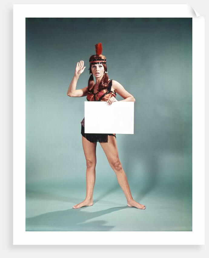 1960s 1970s Character Woman Wearing Native American Feather Headdress Making How Gesture Holding Blank Sign Looking At Camera by Anonymous
