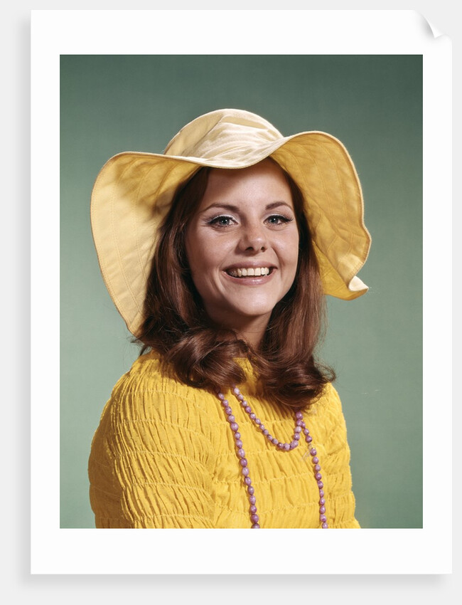 1970s Smiling Young Woman Wearing Yellow Floppy Brim Hat And Blouse With Pink Beads Looking At Camera by Anonymous