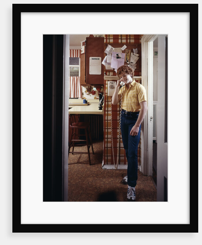 1970s Teenage Boy Talking On Kitchen Wall Phone Telephone by Anonymous