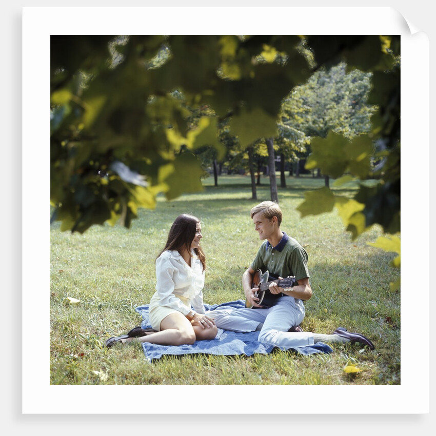 1960 1960s 1970 1970s Retro Smiling Couple Man Woman Sitting On Blanket On Grass Park Man Playing Acoustic Guitar by Anonymous