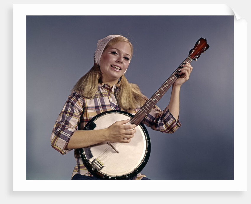 1960s Young Blonde Woman Wearing Plaid Shirt Playing Banjo Singing Folk Music Looking At Camera by Anonymous