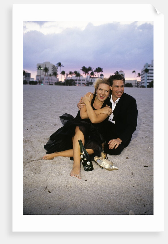 1990s Laughing Couple Man Woman In Formal Wear Sitting Hugging On Beach by Anonymous
