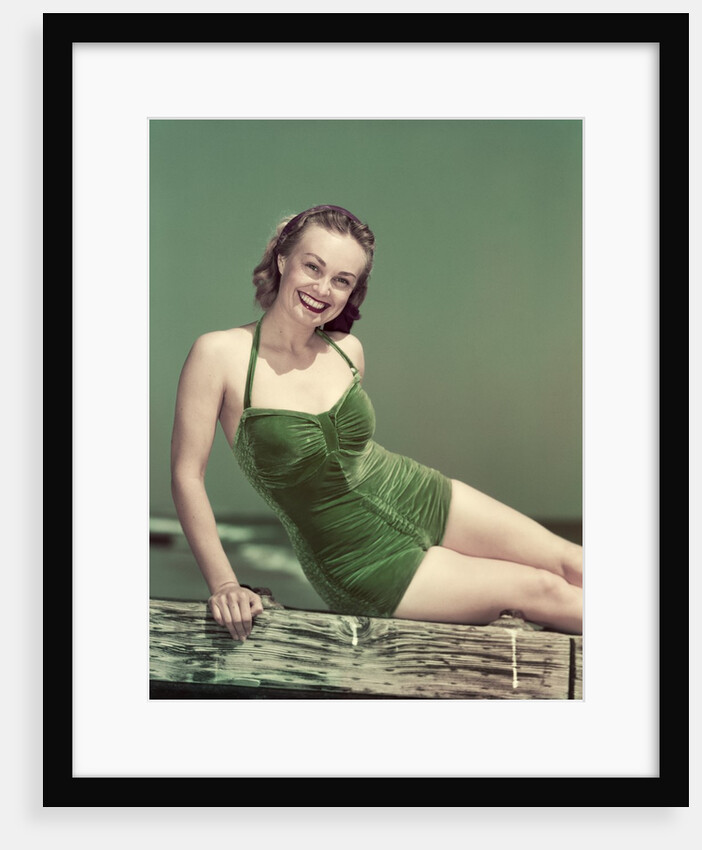 1940s Portrait Smiling Woman Wearing Green Velvet Bathing Suit Sitting Posing On Diving Board by Anonymous