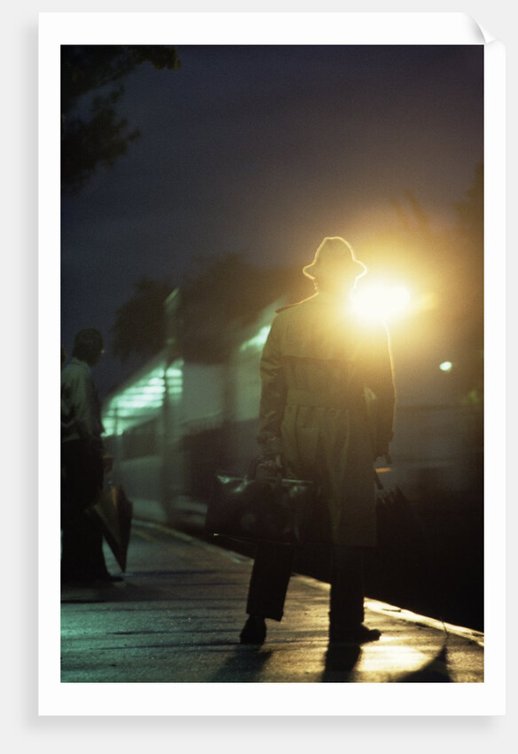 1970s 1980s Anonymous Man Commuter Waiting For Train Silhouetted By Bright Light by Anonymous