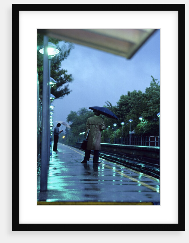 1970s 1980s Anonymous Business Man Holding Umbrella Waiting For A Commuter Train by Anonymous